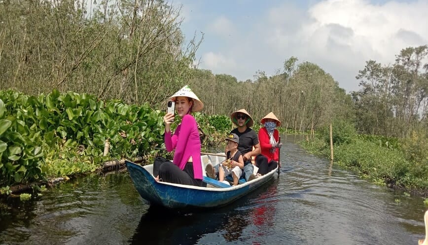 Các cô gái mặc áo bà ba ca hát trên thuyền