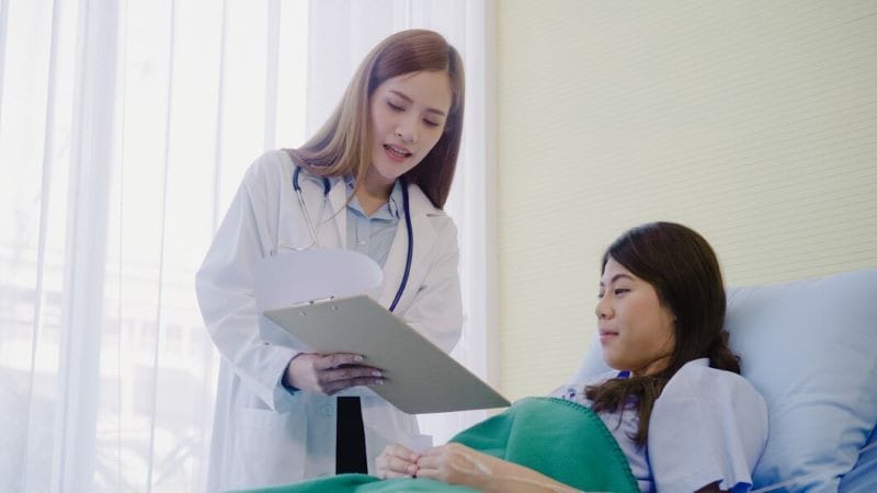 Bệnh nhân đang trao đổi với nhân viên y tế tại quầy tiếp đón, thể hiện sự tiện lợi của hình thức khám ngoại trú.