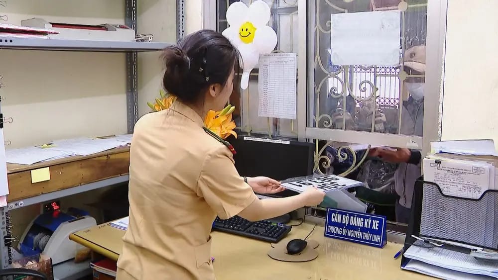 Cán bộ công an hướng dẫn người dân kê khai hồ sơ đăng ký biển số xe máy điện