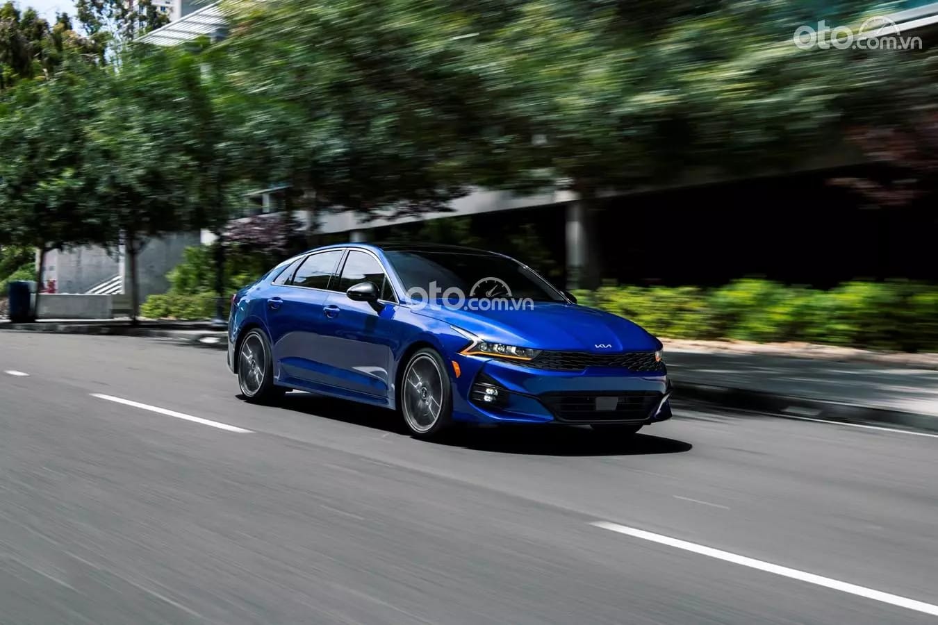 Chiếc KIA K5 màu trắng đang di chuyển trên đường, thể hiện khả năng vận hành mạnh mẽ và ổn định của mẫu xe này.