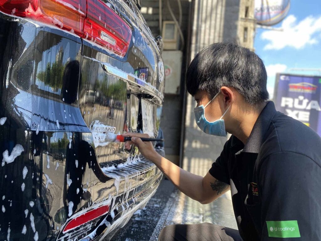 Chuyên gia đang tỉ mỉ chăm sóc xe hơi màu đen, thực hiện detailing ô tô.
