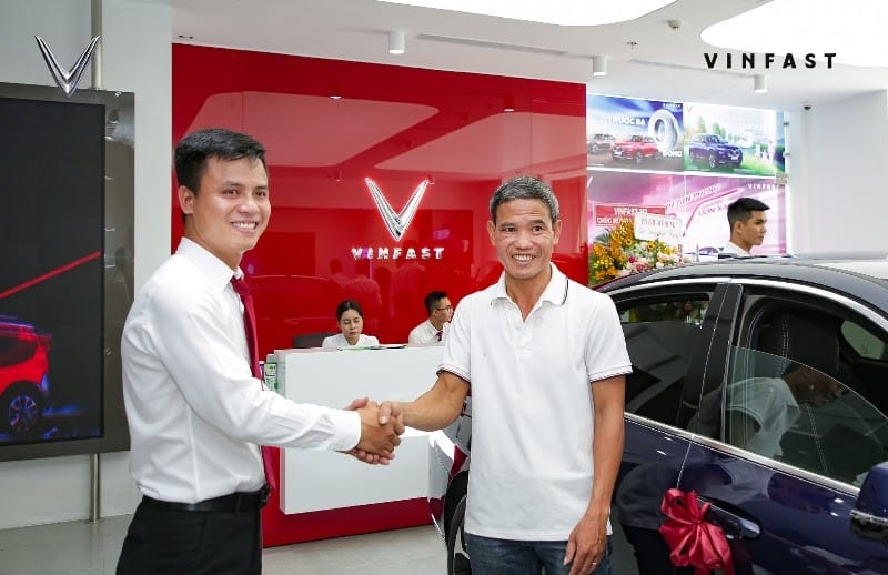 Cố vấn dịch vụ ô tô đang trò chuyện, tiếp nhận yêu cầu từ khách hàng tại quầy lễ tân đại lý.