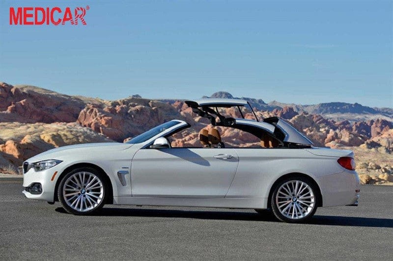 Hình ảnh một chiếc xe Convertible màu xanh đang chạy trên đường bờ biển, thể hiện trải nghiệm lái mở thoáng và sang trọng của dòng xe hơi này
