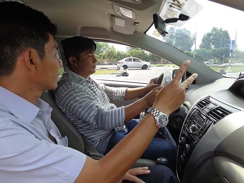Học viên thực hành lái xe ô tô hạng B2 trên sân tập với giáo viên hướng dẫn