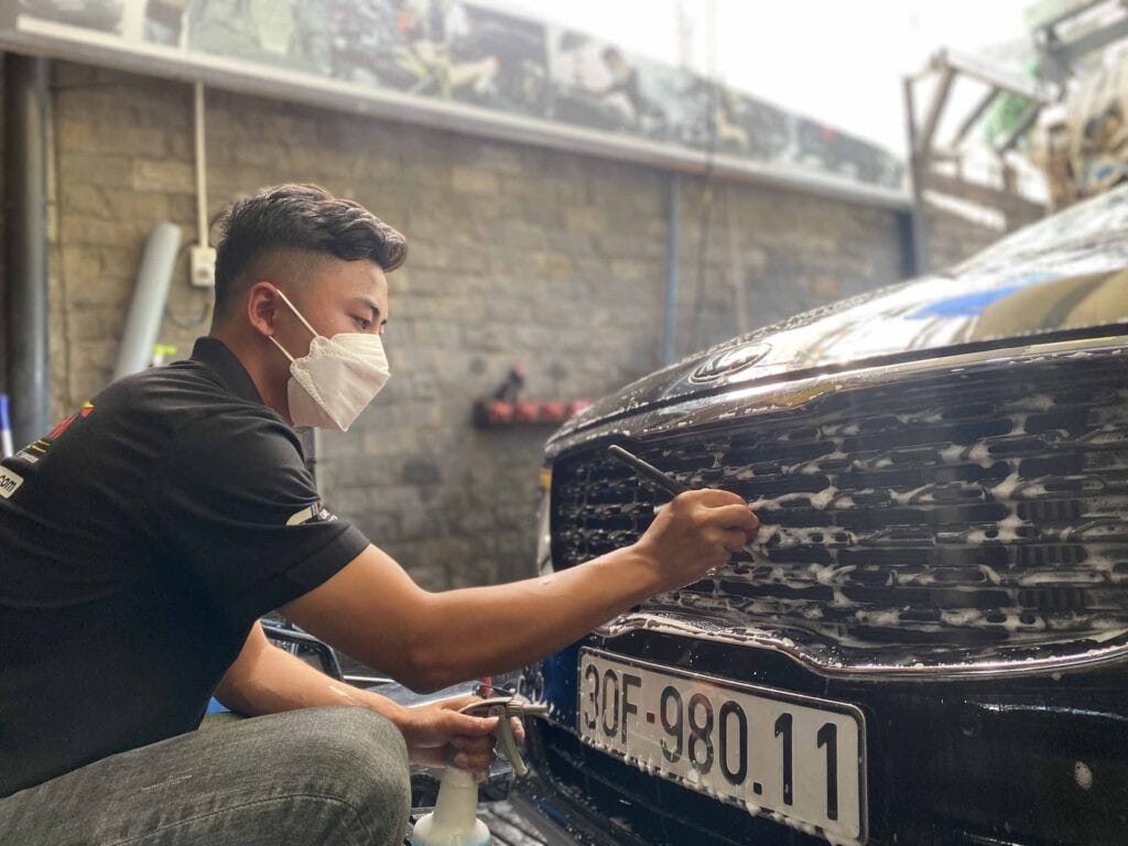 Kỹ thuật viên đang thực hiện chăm sóc xe hơi chuyên nghiệp, chú trọng từng chi tiết nhỏ.