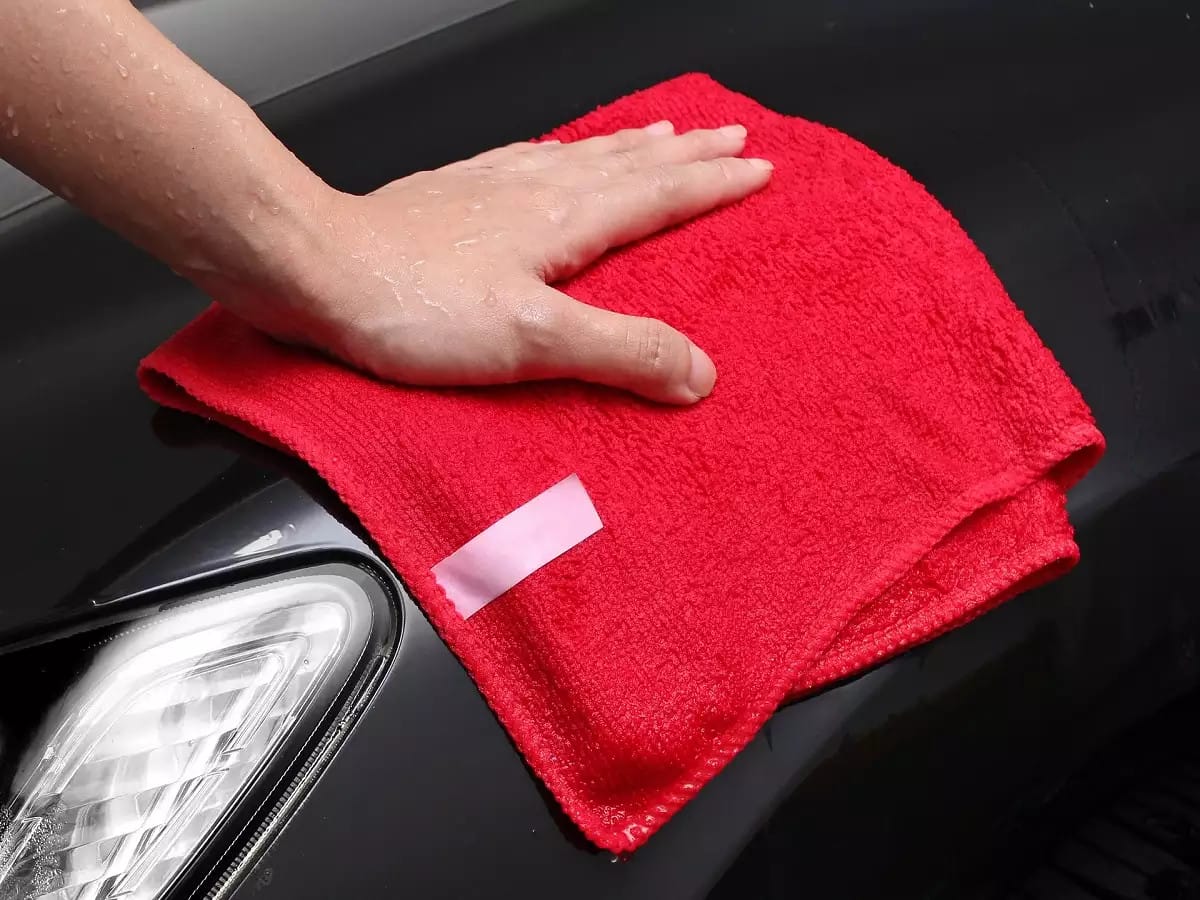 Kỹ thuật viên đang thực hiện đánh bóng bề mặt sơn xe ô tô để loại bỏ vết xước và khôi phục độ bóng đẹp.