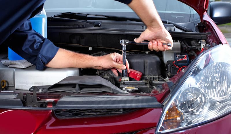 Kỹ thuật viên kiểm tra động cơ xe bám đầy dầu mỡ và bụi bẩn, cần được rửa khoang máy ô tô