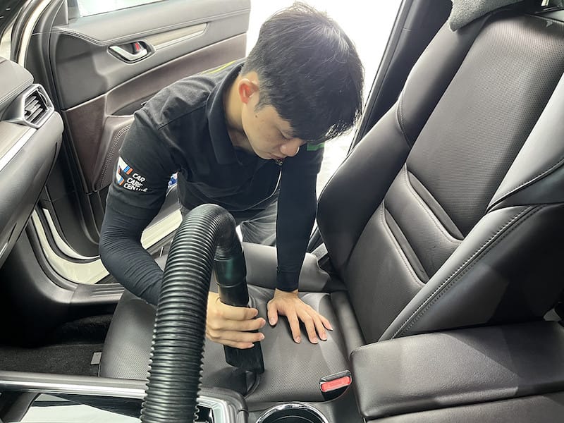 Làm sạch ghế da xe hơi bằng máy hút bụi cầm tay và dung dịch vệ sinh