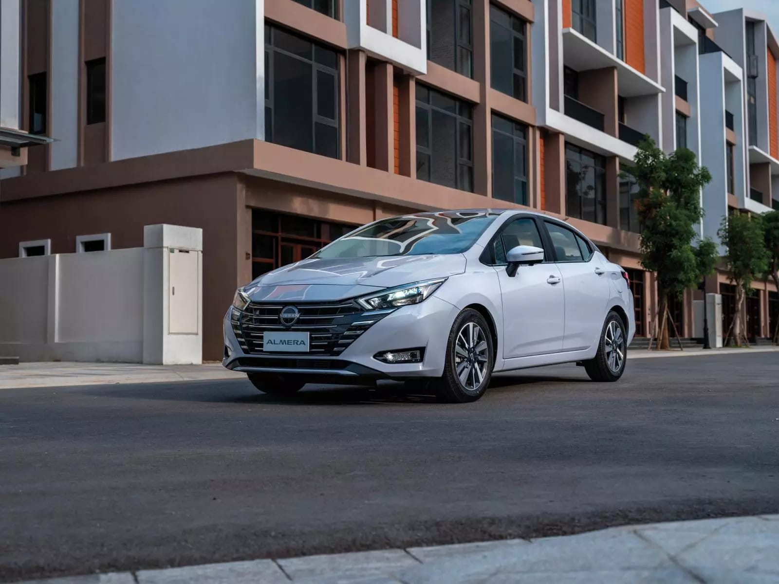 Mẫu xe Nissan Almera màu đỏ cá tính đang đỗ trên đường, nổi bật với thiết kế sedan năng động.