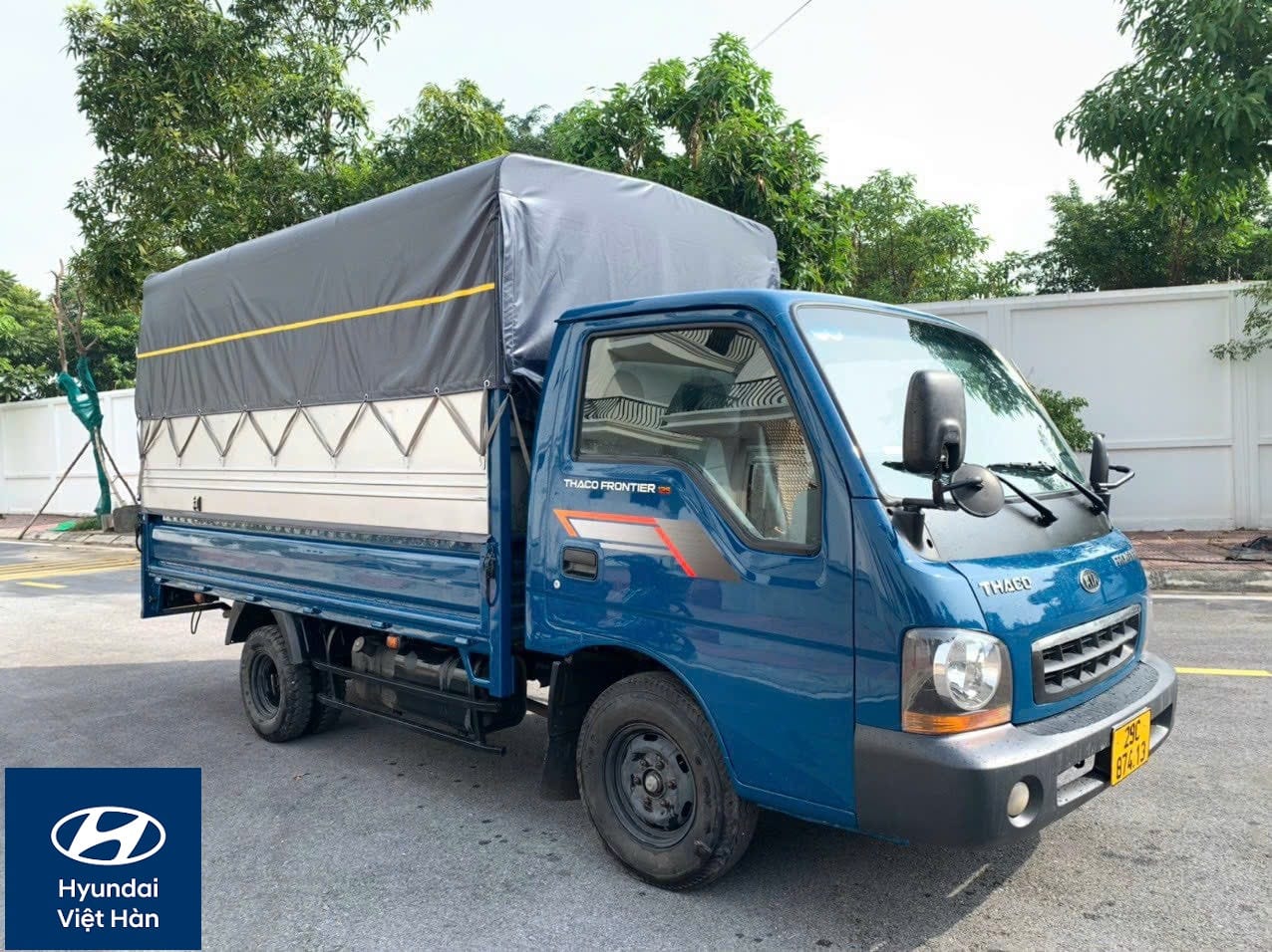 Một chiếc xe tải Kia 1 tấn 25 cũ màu trắng với thùng mui bạt, sẵn sàng cho vận chuyển