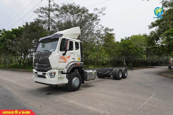 Một chiếc xe tải màu xanh dương đang di chuyển trên đường cao tốc trong điều kiện ánh sáng ban ngày.
