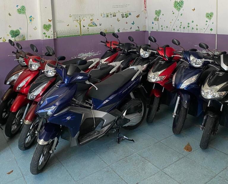 Một chiếc xe tay ga màu đỏ đang đỗ trên vỉa hè tại cửa hàng cho thuê xe máy Vũng Tàu của Mr. Tân