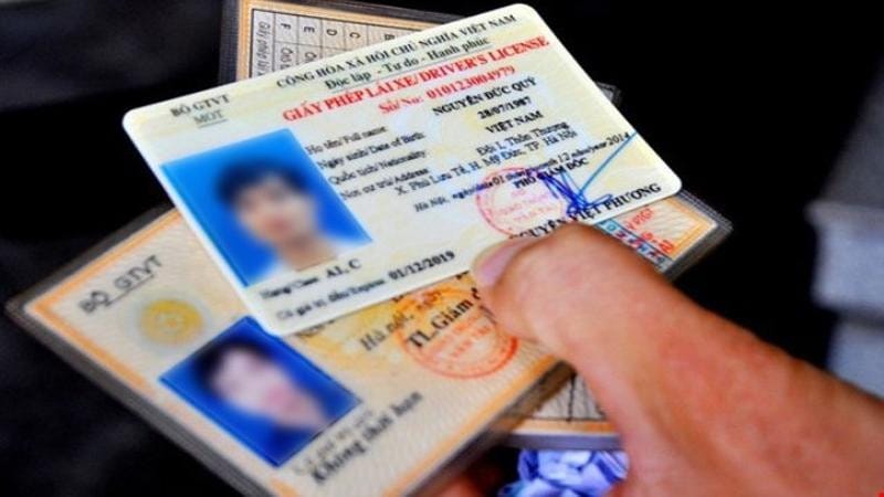 Một người cầm giấy phép lái xe máy PET, minh họa cho các khoản phí thi bằng lái xe máy mới nhất.