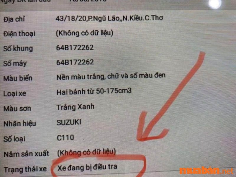 Một người đàn ông đang kiểm tra thông tin xe máy trên điện thoại, bàn tay giữ cà vẹt xe máy.