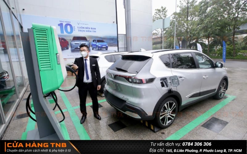 Người dùng đang sạc xe ô tô điện tại trạm sạc, biểu tượng cho xu hướng nên mua xe điện để bảo vệ môi trường
