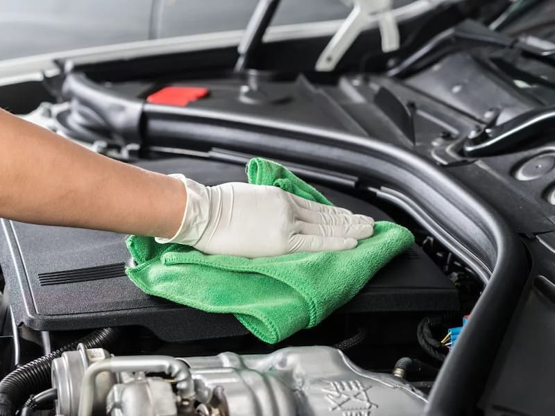 Người dùng đang vệ sinh khoang máy ô tô thường xuyên bằng dụng cụ đơn giản, giúp ngăn chặn tích tụ bụi bẩn.