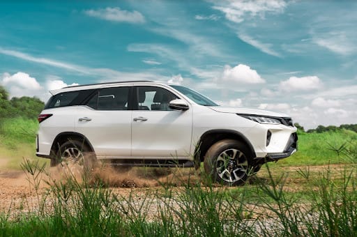 Người lái đang thao tác cần số xe tự động của chiếc Toyota Fortuner để bắt đầu hành trình