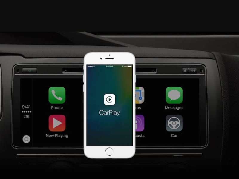 Người lái xe đang tương tác với màn hình ô tô hiển thị CarPlay, tay đặt trên vô lăng