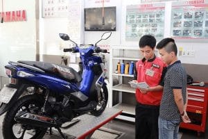 Người thợ đang kiểm tra động cơ xe máy khi xe đề không lên, cần xác định nguyên nhân chính xác để sửa chữa
