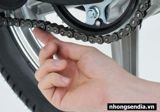 Người thợ đang kiểm tra và điều chỉnh độ căng của dây xích xe máy trên bánh sau