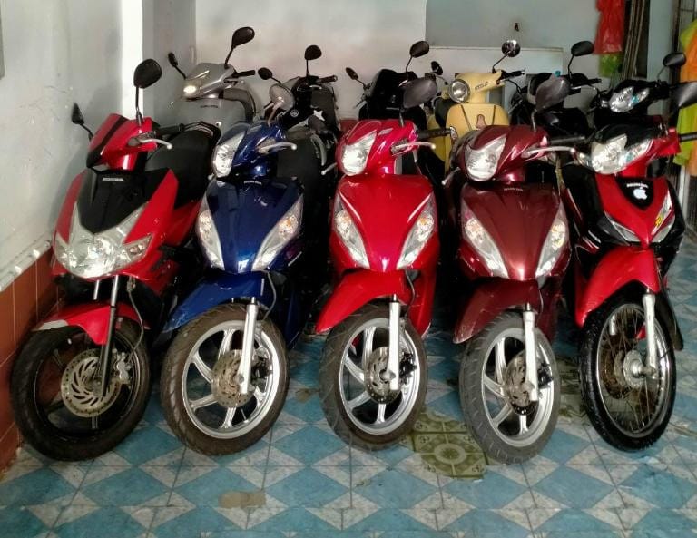 Nữ du khách đang kiểm tra và làm thủ tục thuê xe máy tại Vũng Tàu, với sự hỗ trợ của nhân viên cửa hàng