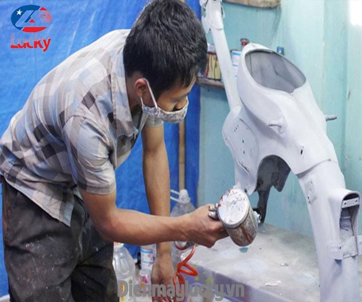 Thợ chuyên nghiệp đang thực hiện dịch vụ xóa vết xước xe máy với trang thiết bị hiện đại