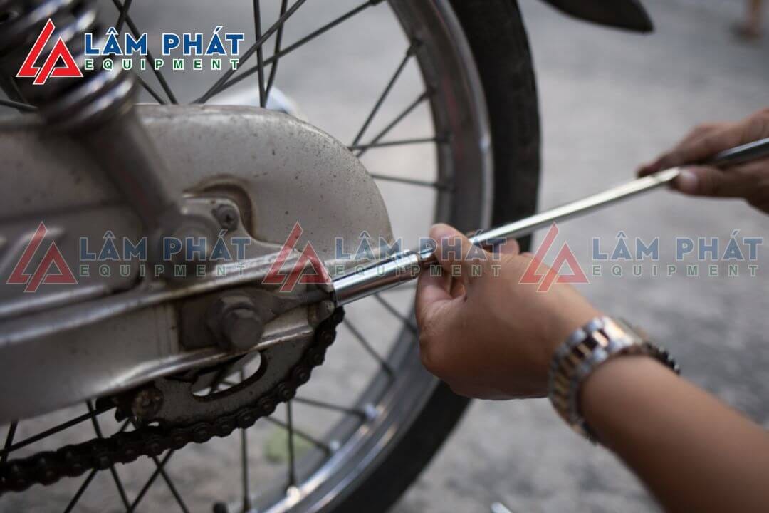 Thợ sửa xe đang tăng xích xe máy