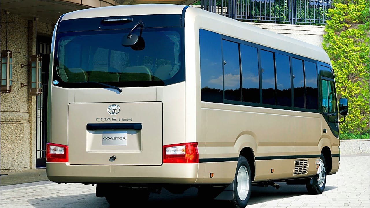 Xe du lịch Toyota Coaster 24 chỗ màu trắng đậu trên đường