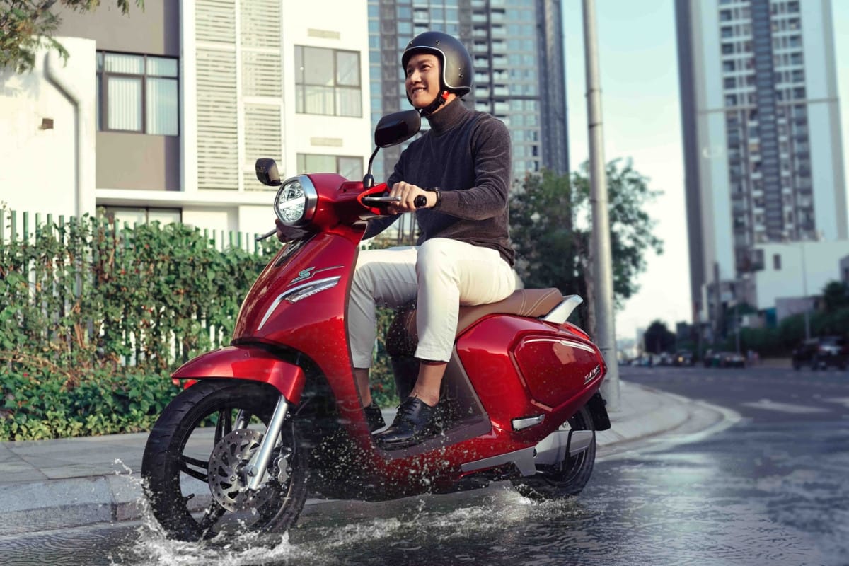 Xe máy điện VinFast Klara S màu xanh đang đi qua vùng nước ngập, minh họa khả năng chống nước IP67