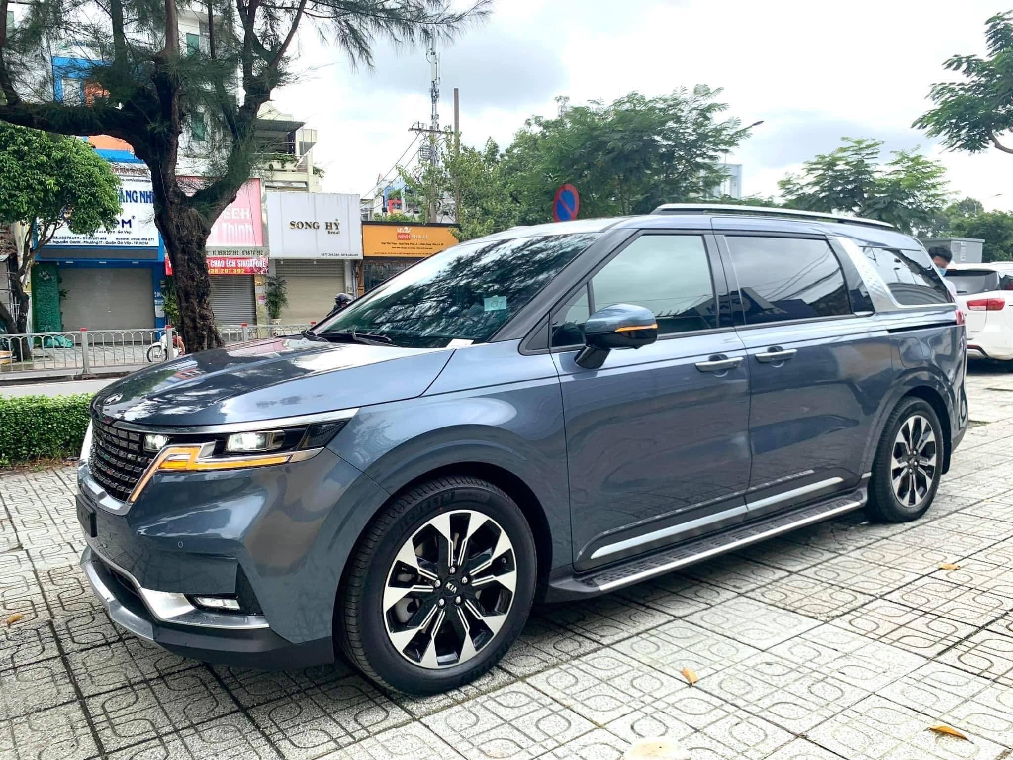 Xe ô tô 7 chỗ màu trắng đậu cạnh biển báo giao thông sẵn sàng cho thuê tự lái quận 12