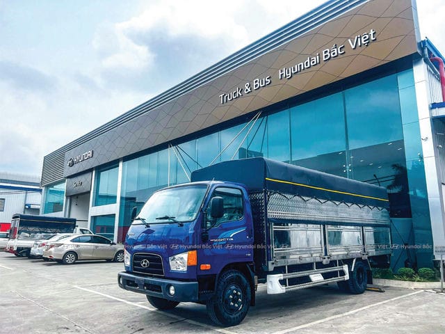 Xe tải Hyundai Mighty 110SL thùng mui bạt màu trắng đang đỗ trên đường.